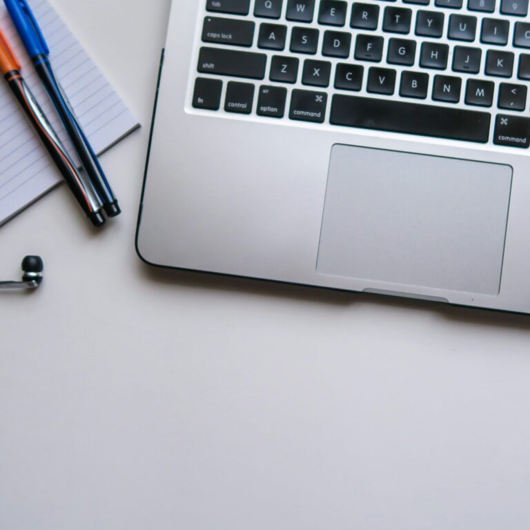 maya-maceka-yW-Qgw_IJXg-unsplash Das Bild zeigt einen Laptop von oben und einen Notizzettel sowie zwei Stifte daneben. Außerdem ragen Knop-Kopfhörer mit Kabeln ins Bild.